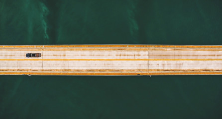 Aerial top view of a long highway bridge above a river. Highway on horizontal, isolated by the green water of the river. Bridge Helio Serejo over the Parana river, Brazil.
