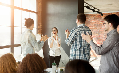 Young team clapping hands to colleague at meeting