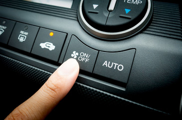 Finger pressing on Power switch of a Car air conditioning system