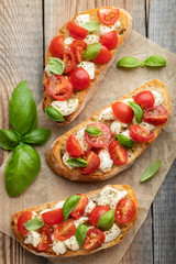 Bruschetta with tomatoes, mozzarella cheese and basil on a old rustic table. Traditional italian appetizer or snack, antipasto. Top view. Flat lay