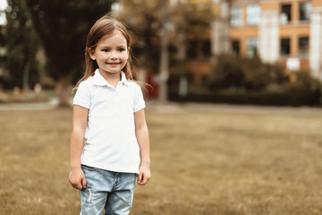 Fototapeta premium Waist up portrait of little girl spending time outdoors. She is looking sideways and smiling with delight. Copy space in right side