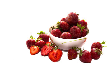 Heap of fresh strawberry put in white ceramic bowl, and some strawberry spread on white table.