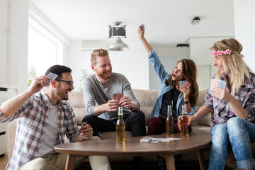 Happy group of friends playing cards and drinking