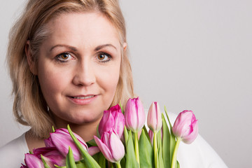 Portrait of an attractive overweight woman with tulips in studio on a white background.