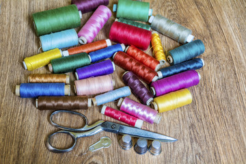 Multi Colored Thread Yarns and Vintage Scissors on Wooden Background 