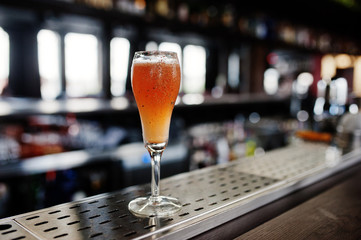 Alcoholic long cocktail with cinnamon at bar table.