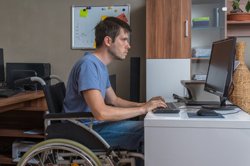 Disabled man is sitting on wheelchair and working in office.