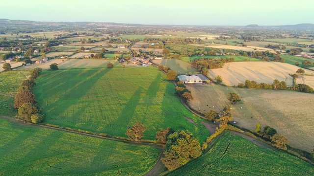 Aerial view, pan move. Cheshire plains and green fields during sunset