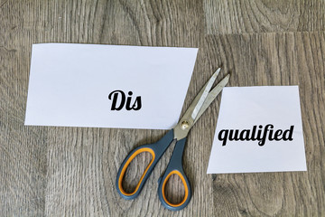 Change of Disqualified to Qualified with Scissors on a Wooden Background