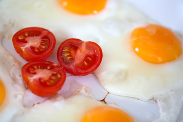 Fried eggs with cherry tomatoes .
