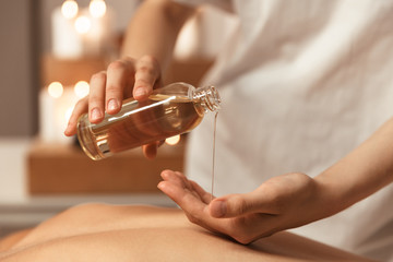 Close up of a woman masseur pouring massage oil - obrazy, fototapety, plakaty