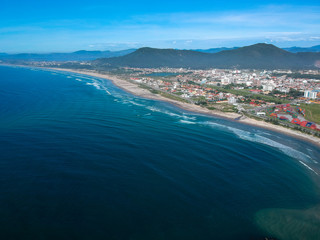  Aerial view of Brazilian beach with white sand, blue sea, and harbor.