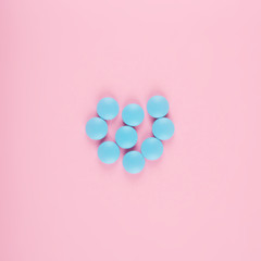 Blue pills isolated on pastel coloured background. Medication and prescription pills flat lay background.