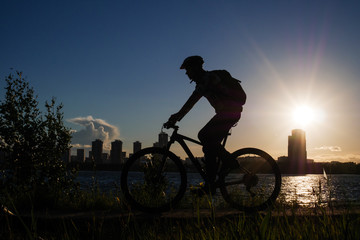 Fototapeta na wymiar Photo of bicyclist wearing helmet riding around city in evening