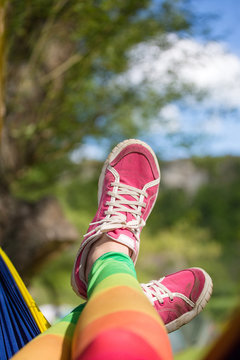 Photo of crossed woman legs in pink sneakers in tent