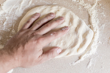 Man's hand and dough. Preparation of dough.