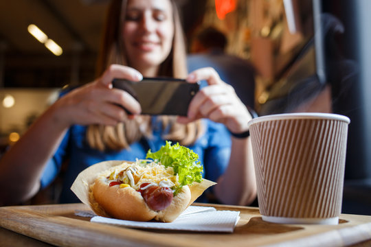 Young woman taking photo of her lunch in cafe or restaurant.