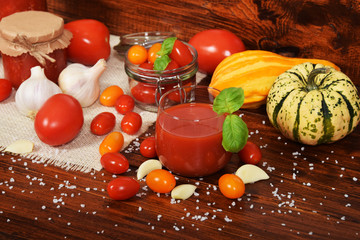 colorful decorative pumpkins next to a glass of tomato juice