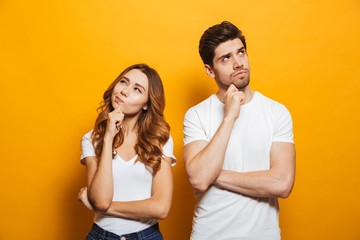 Image of happy young people man and woman in basic clothing thinking and touching chin while...