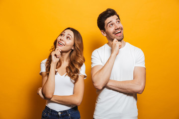 Image of cheerful young people man and woman in basic clothing laughing and touching chin while...