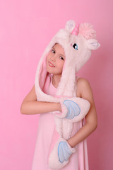 little girl in a hat with  unikorn  on a pink background.