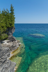 Fototapeta premium Lake Huron shoreline blue green water and limestone rocks along the Georgian bay lake shore landscape