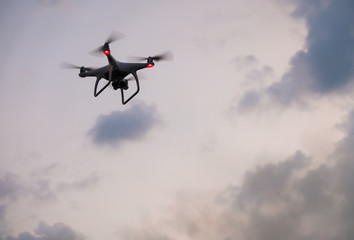 Fototapeta na wymiar Drone is flying. Modern technological background - silhouette of flying machine in cloudy sky.
