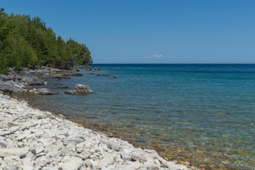 Fototapeta na wymiar Lake Huron shoreline blue green water and limestone rocks along the Georgian bay lake shore landscape