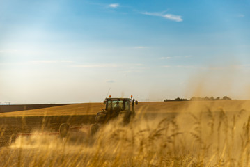 Fototapeta premium Le fermier sur son tracteur agricole prépare sa terre pour aérer les sols en formant de la fumée de poussière