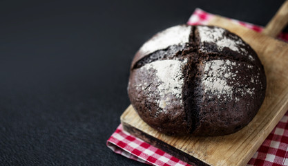Fresh bread on black chalkboard background. Top view with copy space. Rye Bread on cutting board closeup.