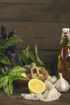 Many food ingredients for making pesto on dark wooden background