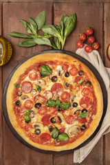 Pepperoni pizza closeup with cherry tomatoes and basil leaves