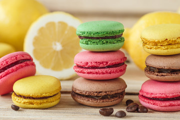 Green, pink, yellow and brown french macarons with lemon and coffee beans