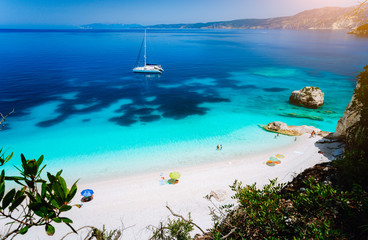 Fteri beach, Cephalonia Kefalonia, Greece. White catamaran yacht in clear blue sea water. Tourists...