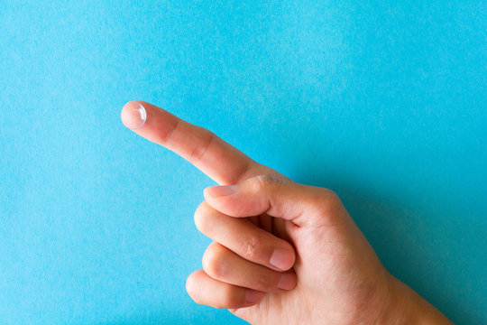 Contact lens on finger on blue background