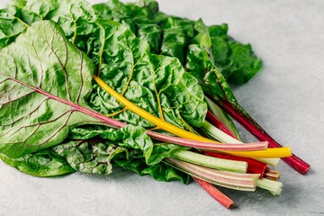 Fresh raw swiss rainbow chard leaves on gray background.