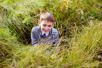 boy in black and white jacket in autumn laughing in grass