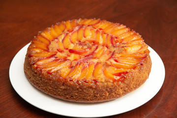 Cake with nectarines on white plate on top of dining table