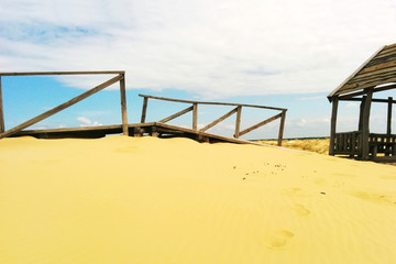 Obraz na płótnie Canvas Desert landscape. Wooden structures on sand.