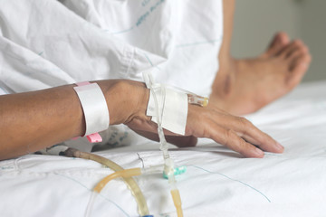 Sickness of hands with intravenous to patient's on white blanket