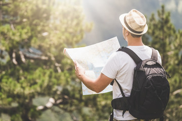 Backpacker with the map on the top of the mountain