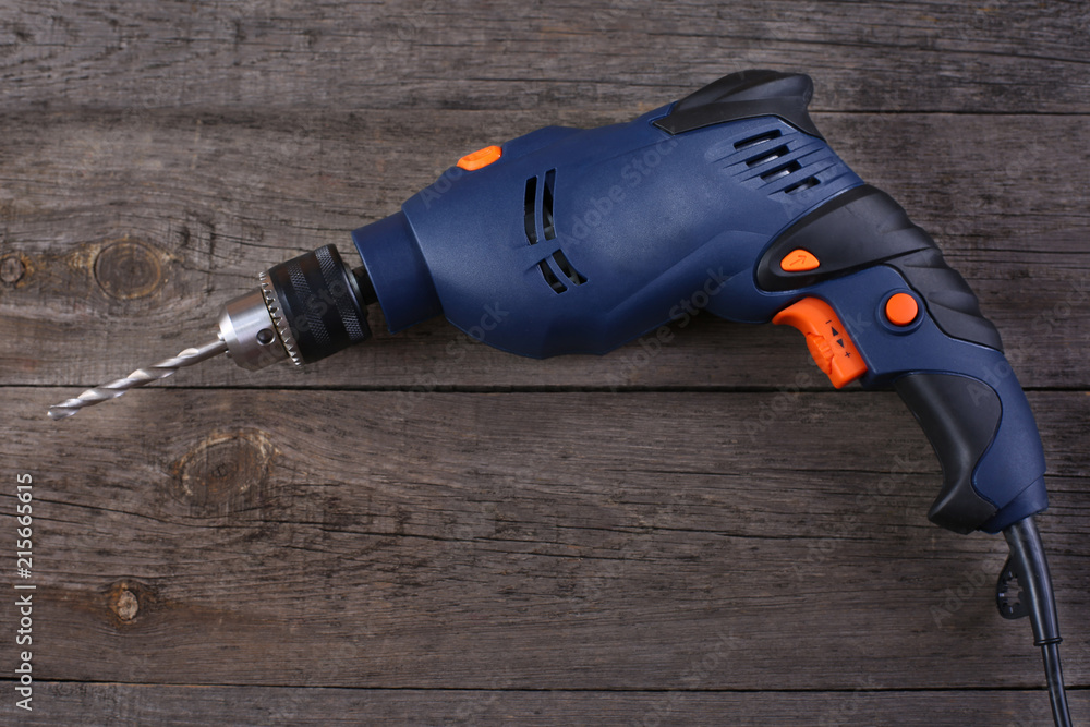 Wall mural Electric drill on wooden background