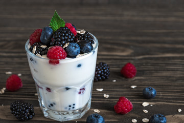 healthy yogurt with fresh forest berries in a glass on rustic wooden background. healthy diet breakfast
