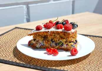 a piece of cake with white cream, fresh raspberry, black currant