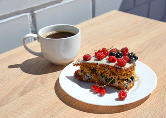 a Cup of coffee, a piece of cake with white cream, fresh raspber