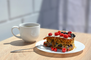 a Cup of coffee; a piece of cake with white cream; fresh raspber