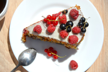 a piece of cake with white cream, fresh raspberry, black currant