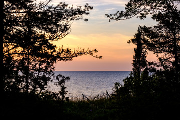 colorful sunset by the lake with trees and red sky in background