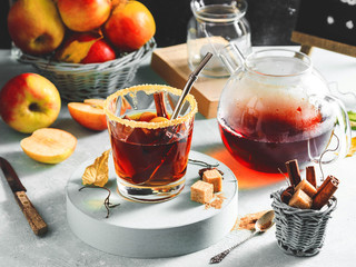 Apple cider drink, hot cocktail with cinnamon sticks and apple slices. Tea with spices. Autumn cozy mood