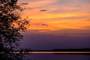 colorful sunset by the lake with trees and red sky in background